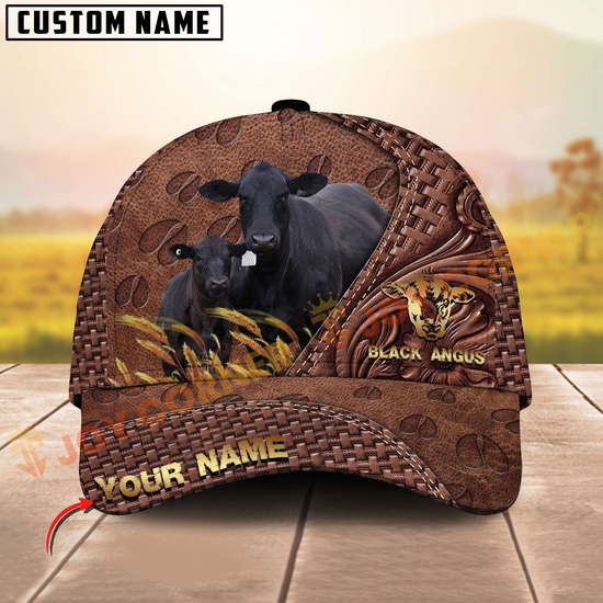 Brown leather cap with black Angus cattle design on a wooden surface with a blurred natural background.