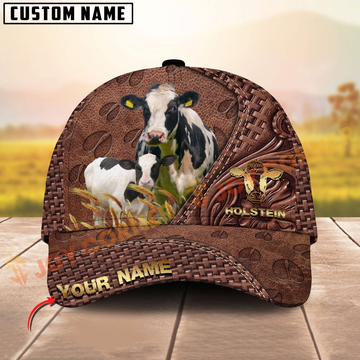 Brown leather cap with cow design and 'Holstein' text on a wooden surface with blurred field background.