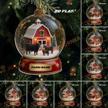 Christmas ornament with a barn and cows inside a snow globe, displayed on a tree.