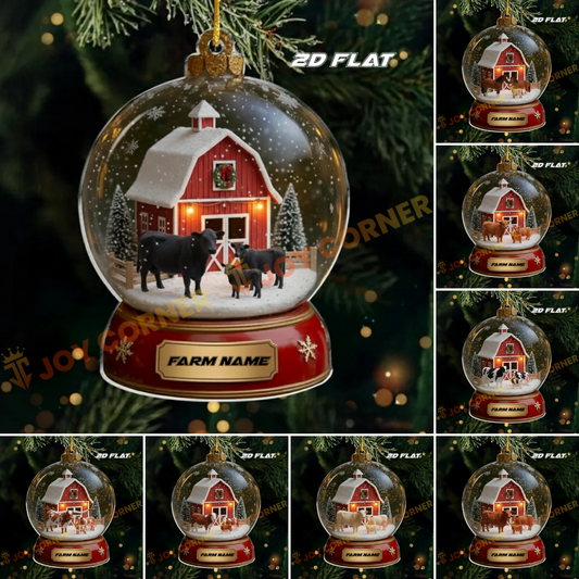 Christmas ornament with a barn and cows inside a snow globe, displayed on a tree.