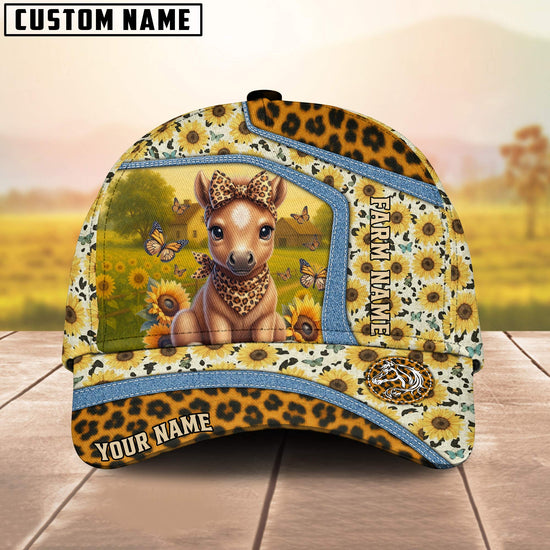 Cap with a design of a deer in a field, surrounded by sunflowers and butterflies, on a wooden surface with a blurred natural background.